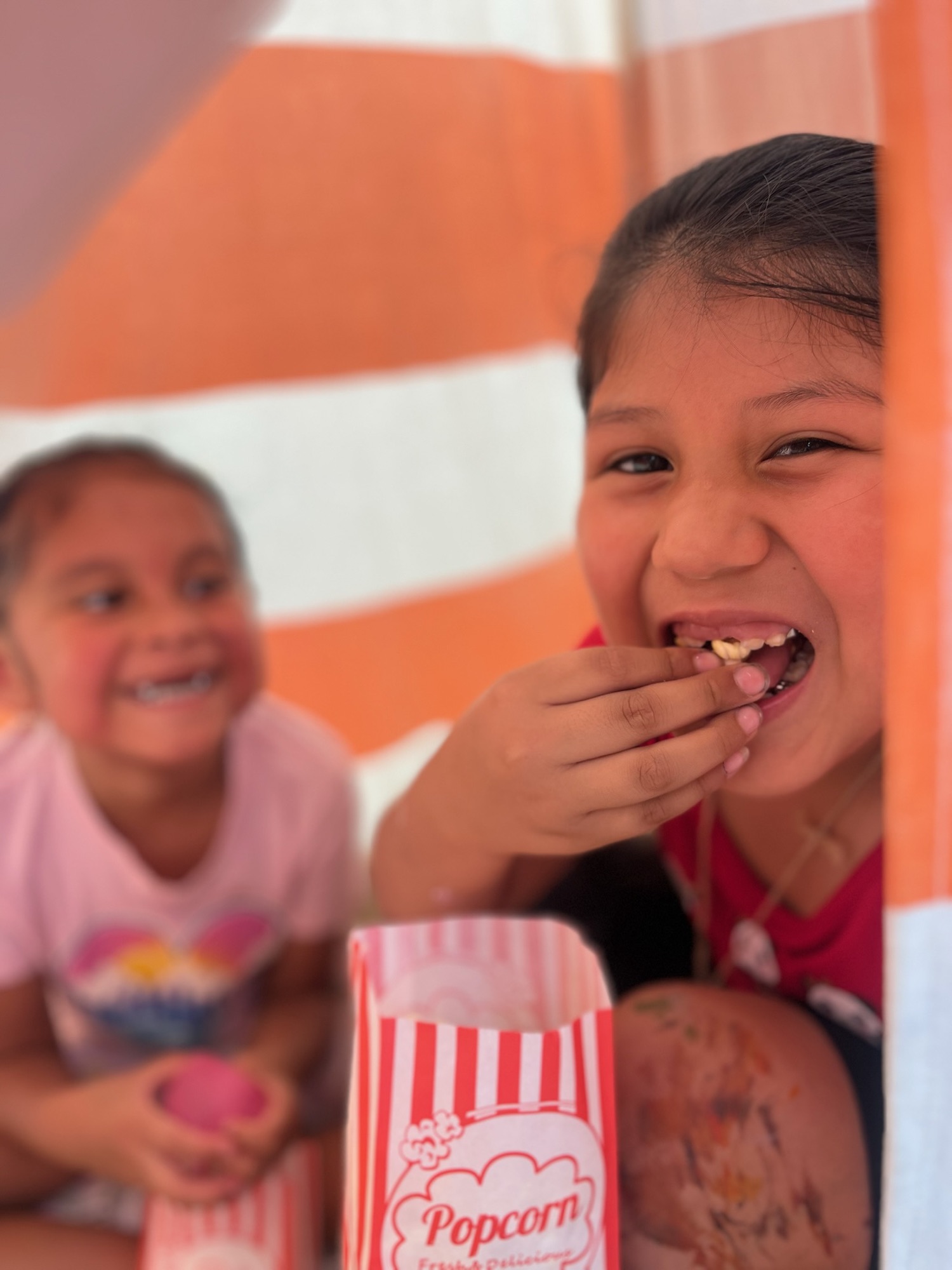 Two girls smiling and eating popcorn