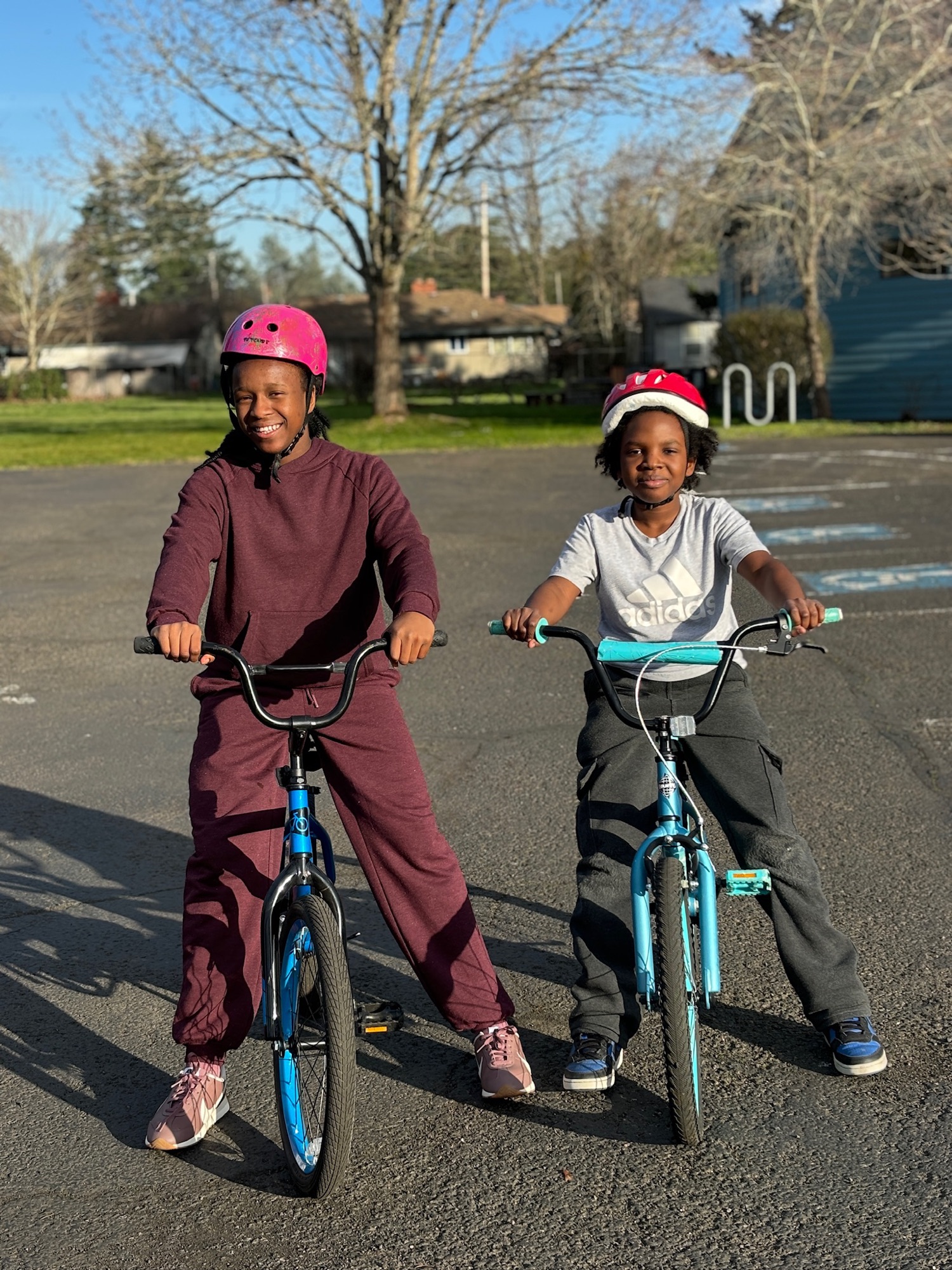 Two kids in helmets smiling on their bikes