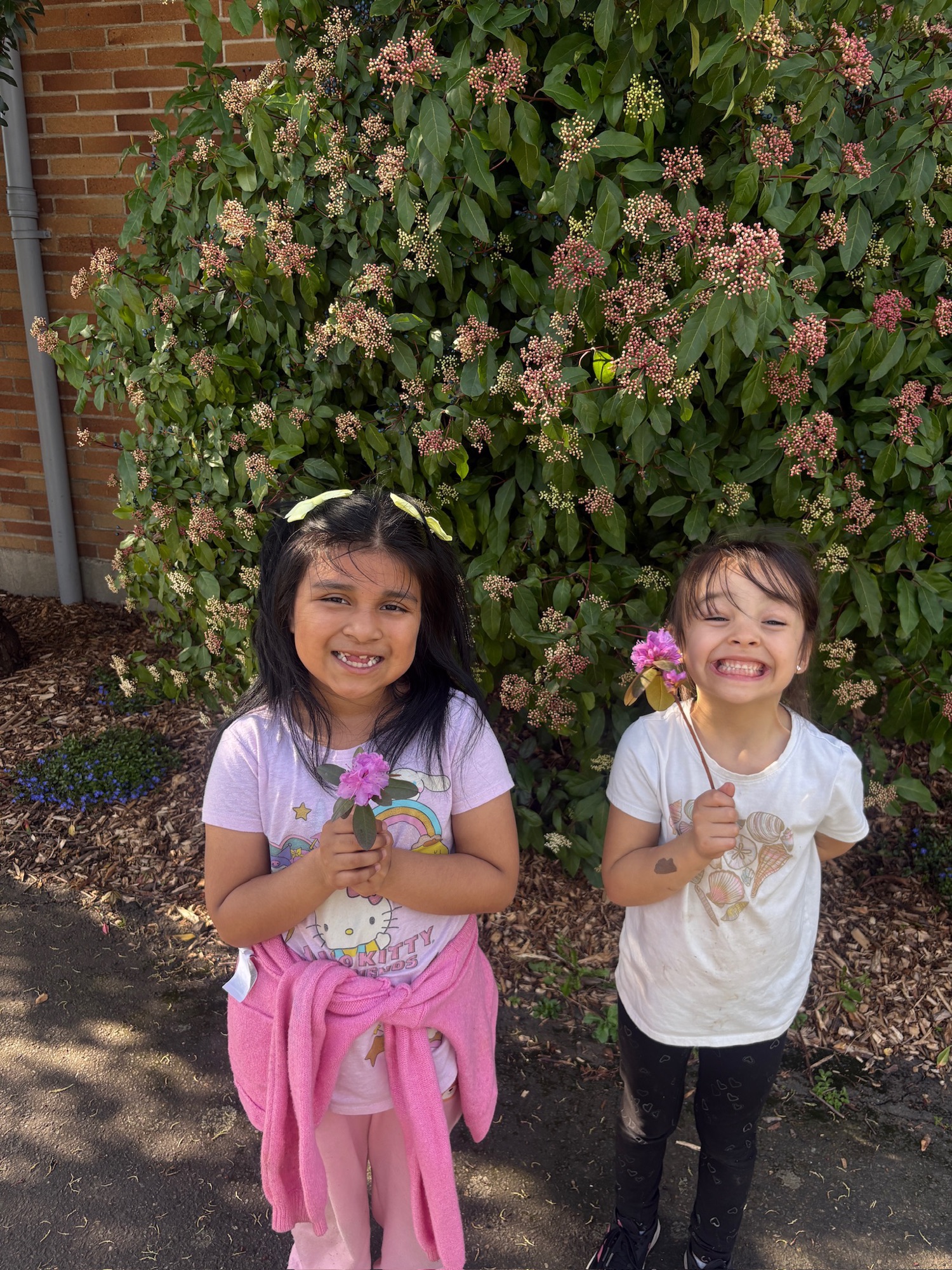 Two smiling girls holding flowers