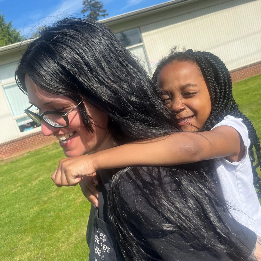 A smiling We Belong mentor giving a girl a piggyback ride
