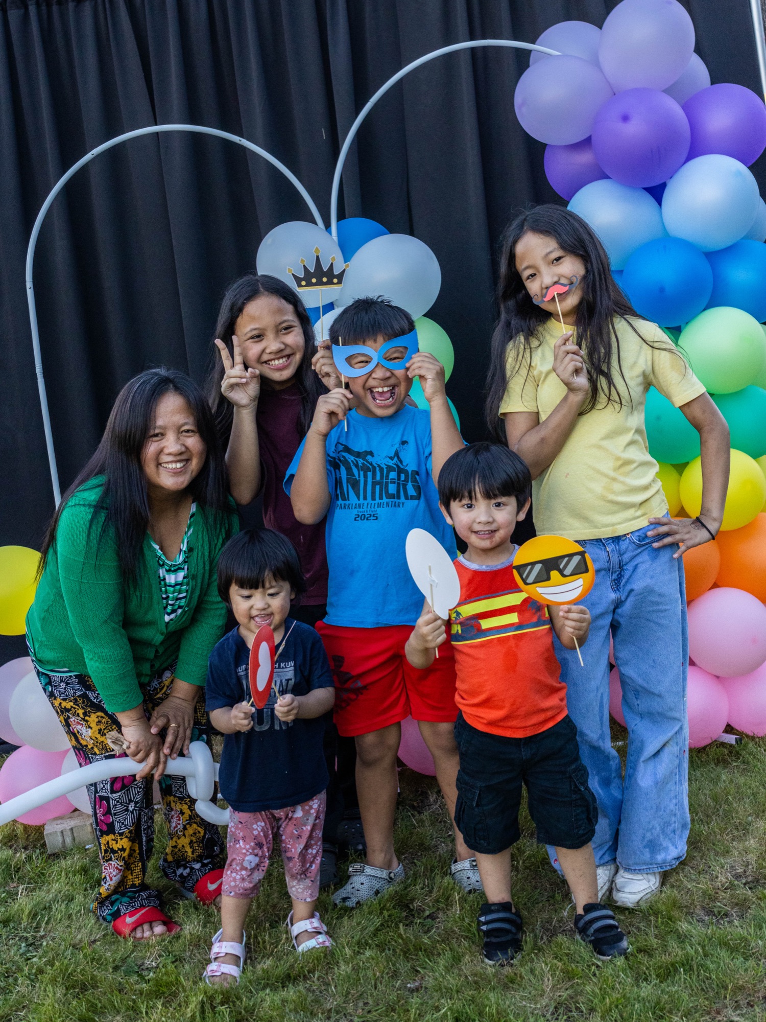 A mom and her six kids posing with fun props at the Family Celebration photo booth